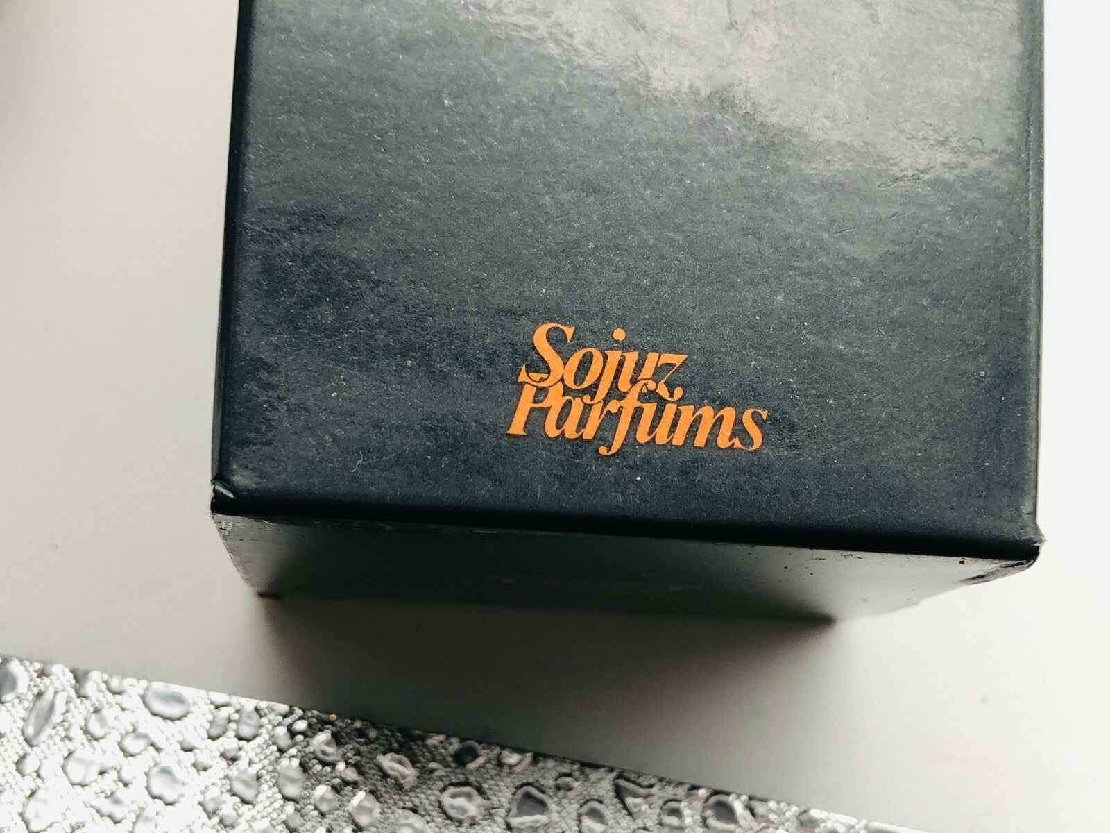 Scatola del Profumo Tabiti Sojuz Vintage con logo Sojuz Parfums in arancione su sfondo nero