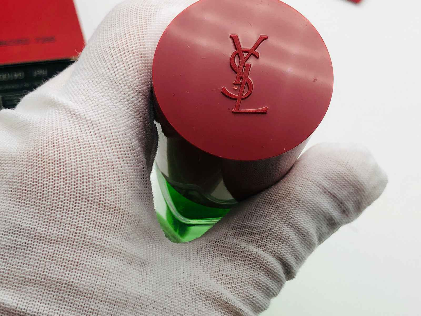 Dettaglio del tappo di Ysl Pour Homme Vintage con logo YSL su fondo rosso