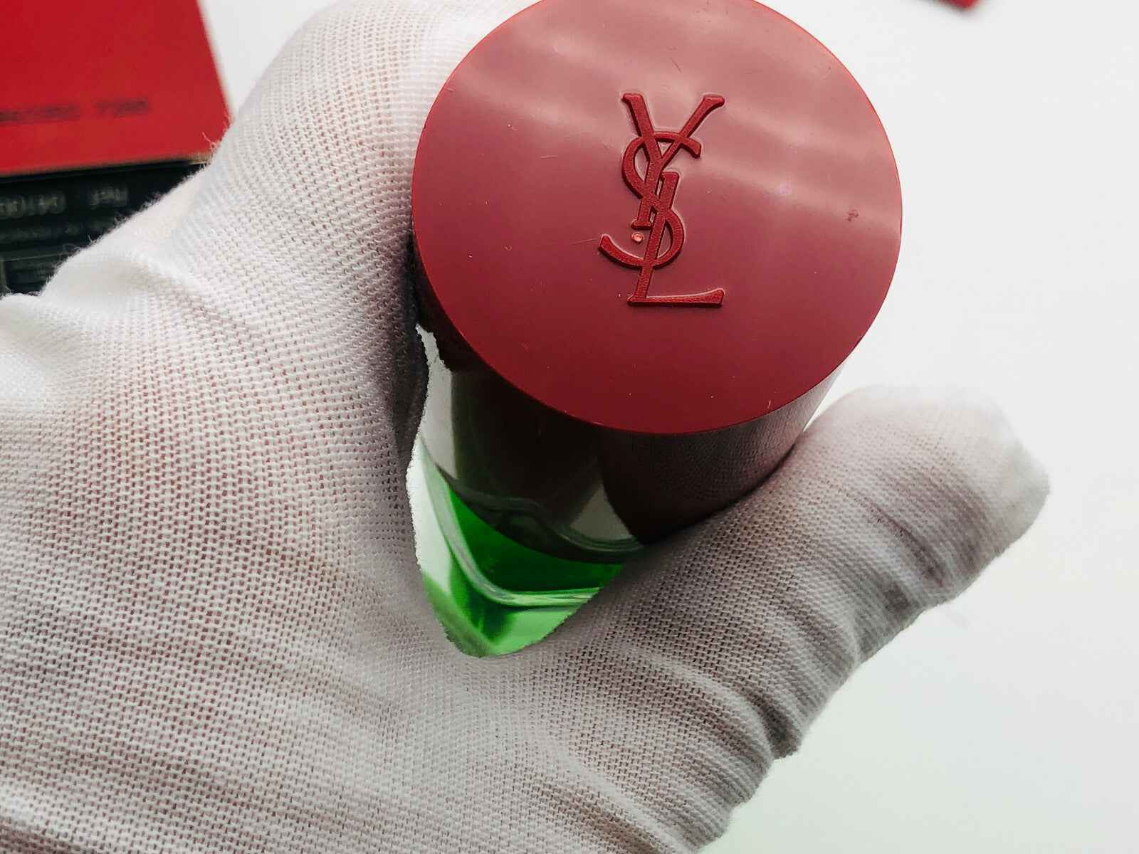 Dettaglio del tappo di Ysl Pour Homme Vintage con logo YSL su fondo rosso