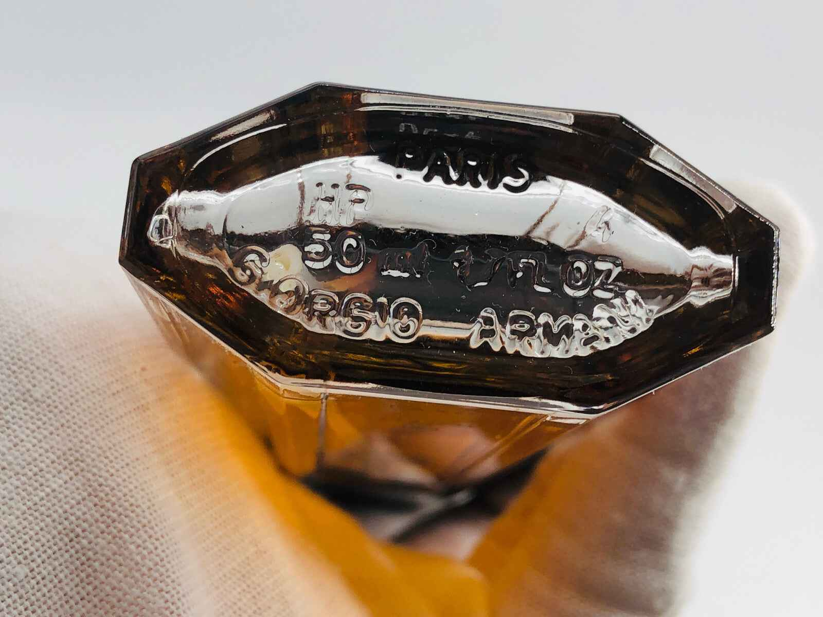Dettaglio del fondo di un profumo vintage Armani con etichetta argentata e design elegante