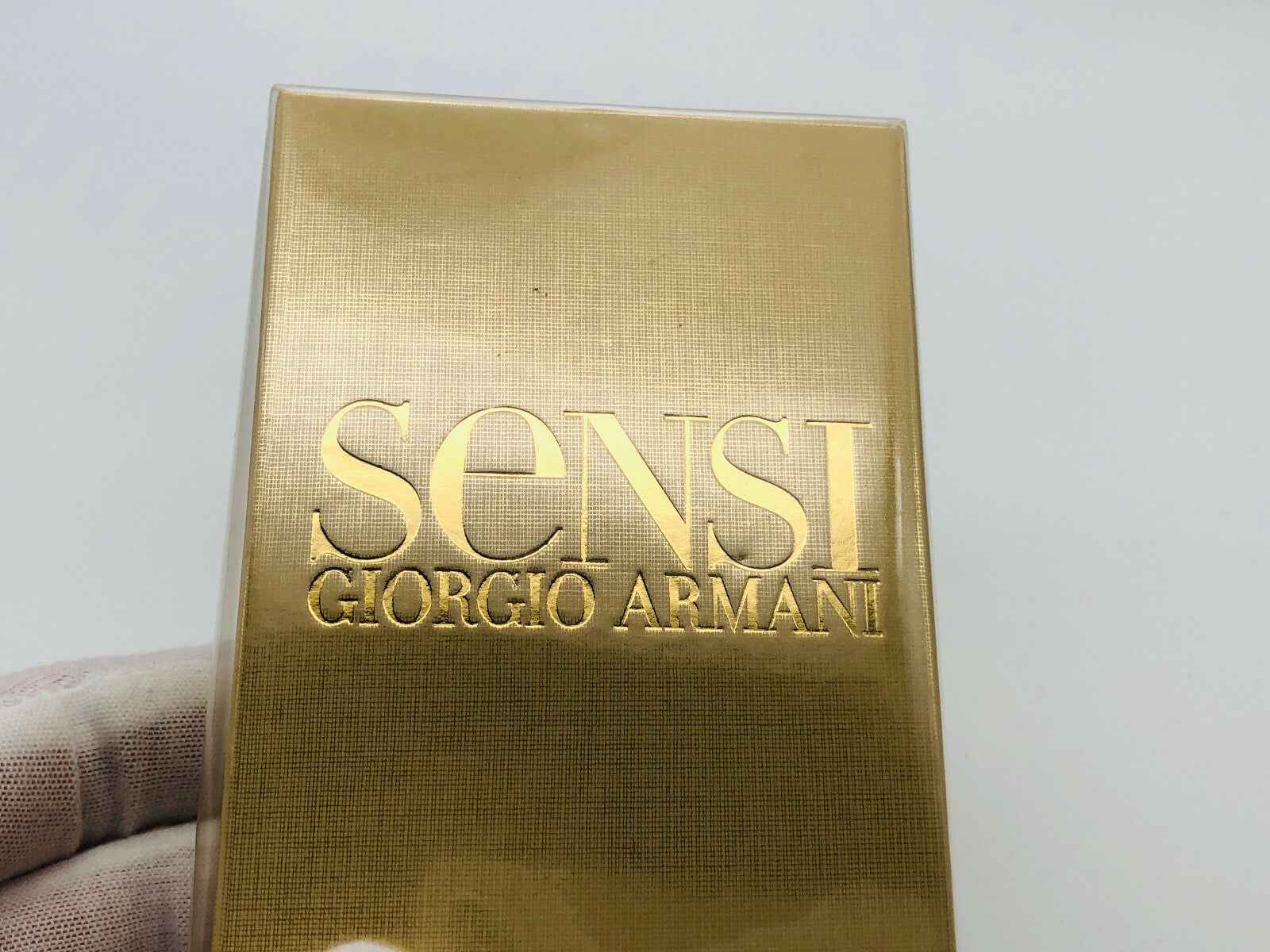 Scatola del profumo Armani Sensi in oro con logo Giorgio Armani in rilievo