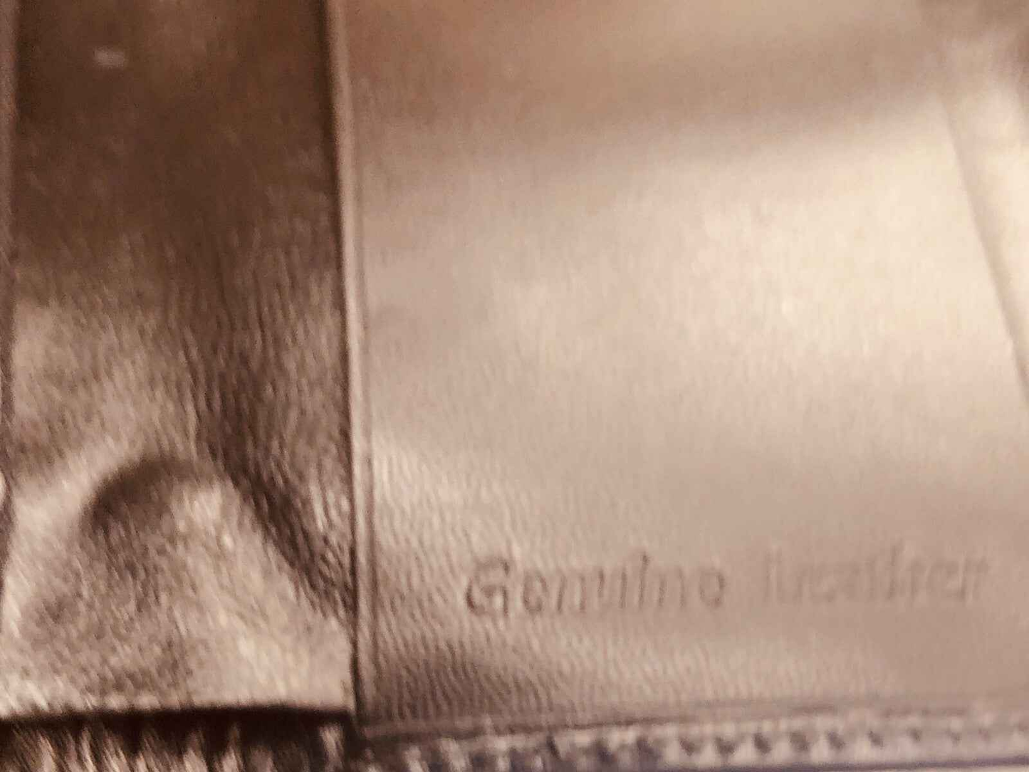 Dettaglio di una borsa in vera pelle con etichetta Genuine Leather, prodotto Azzaro Pour Homme profumo vintage.