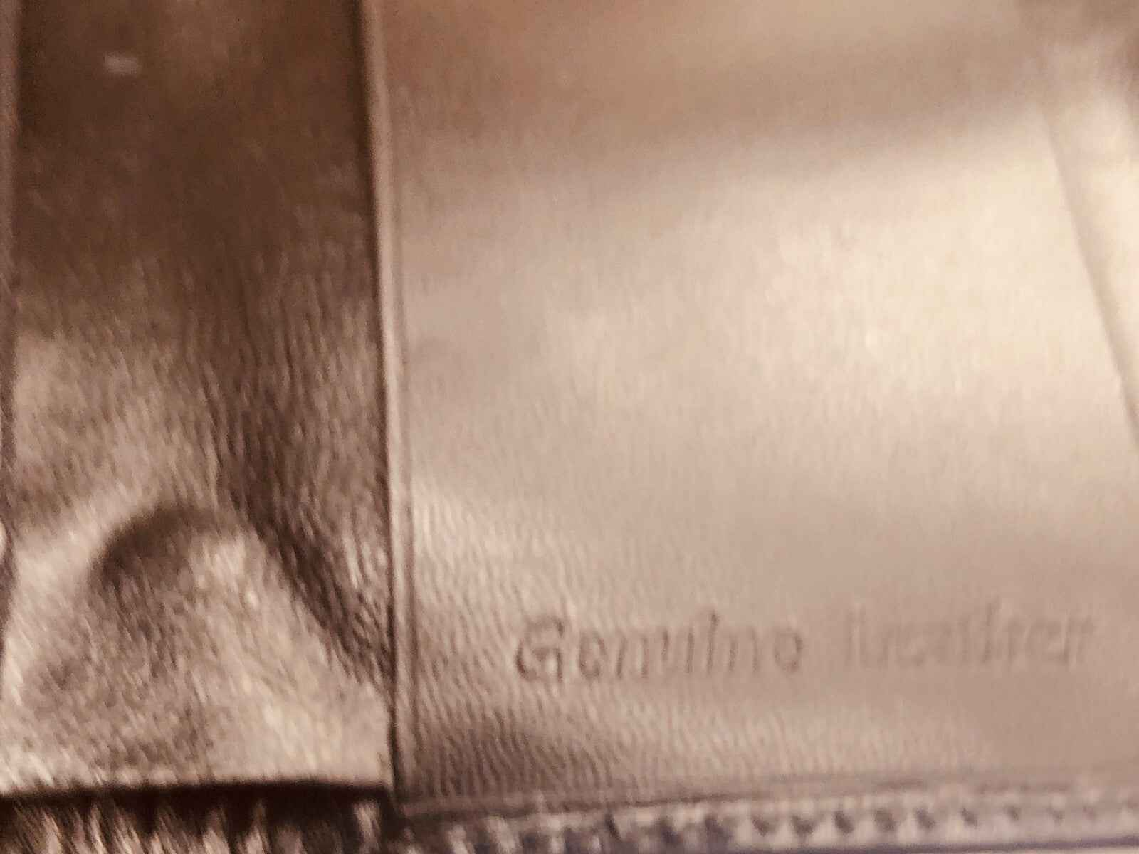 Dettaglio di una borsa in vera pelle con etichetta Genuine Leather, prodotto Azzaro Pour Homme profumo vintage.