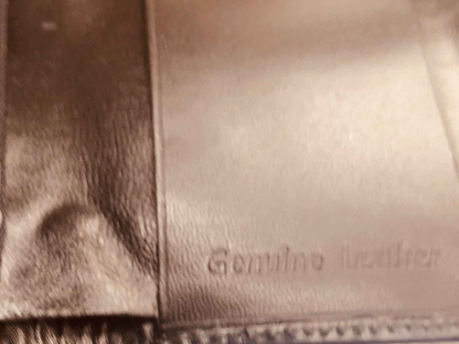 Dettaglio di una borsa in vera pelle con etichetta Genuine Leather, prodotto Azzaro Pour Homme profumo vintage.