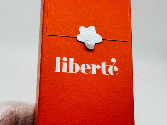 Scatola arancione del profumo Cacharel Liberte Vintage con chiusura decorativa stilizzata