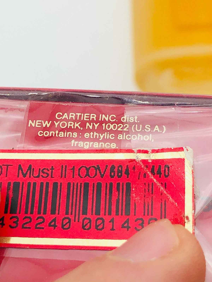 Attacco dettagliato del profumo Must De Cartier con informazioni e codici a barre sul retro della confezione