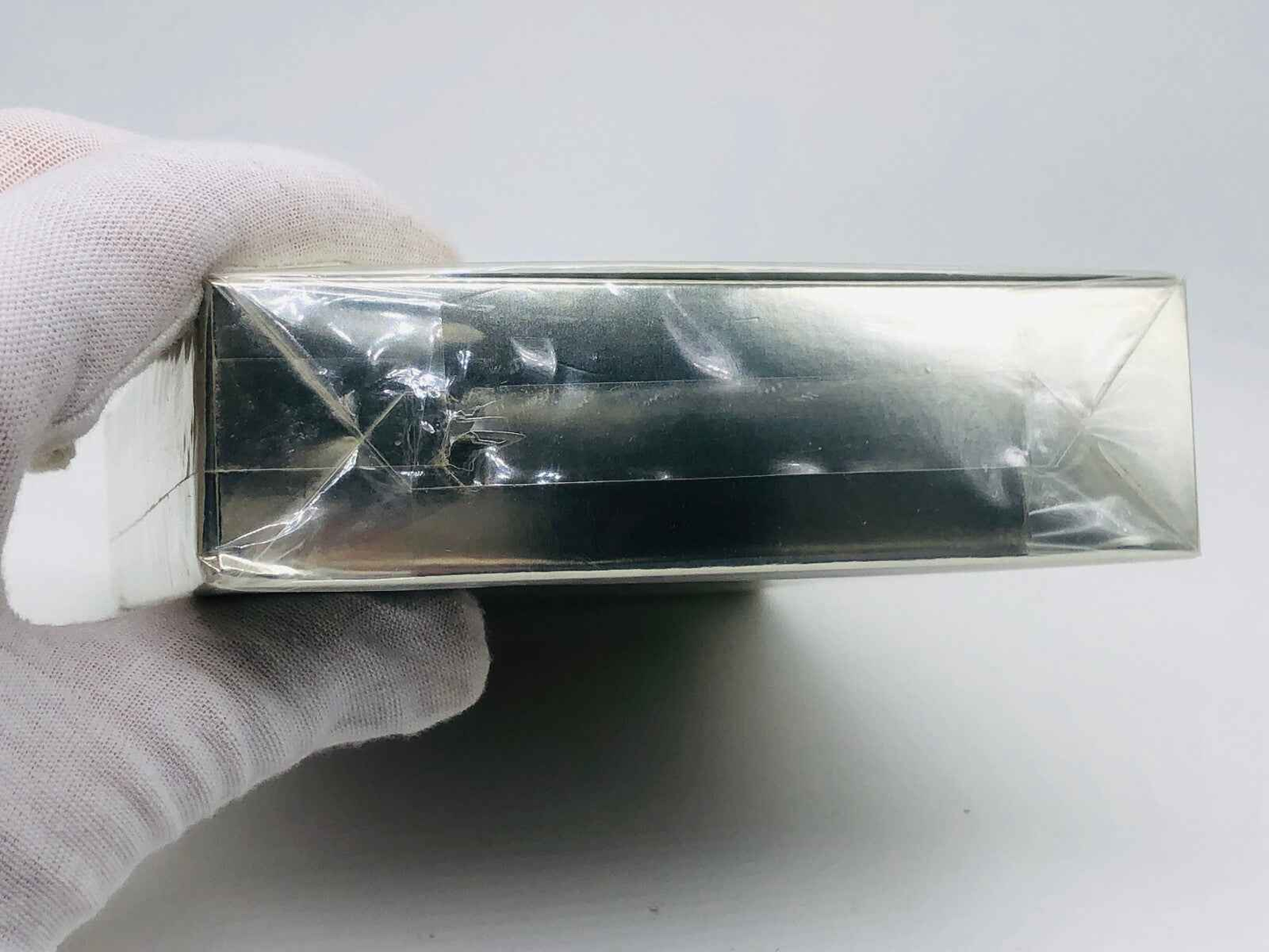 Scatola del profumo Cartier Must con finitura argentata, tenuta da una mano guantata