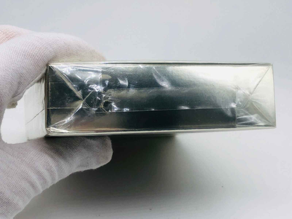 Scatola del profumo Cartier Must con finitura argentata, tenuta da una mano guantata