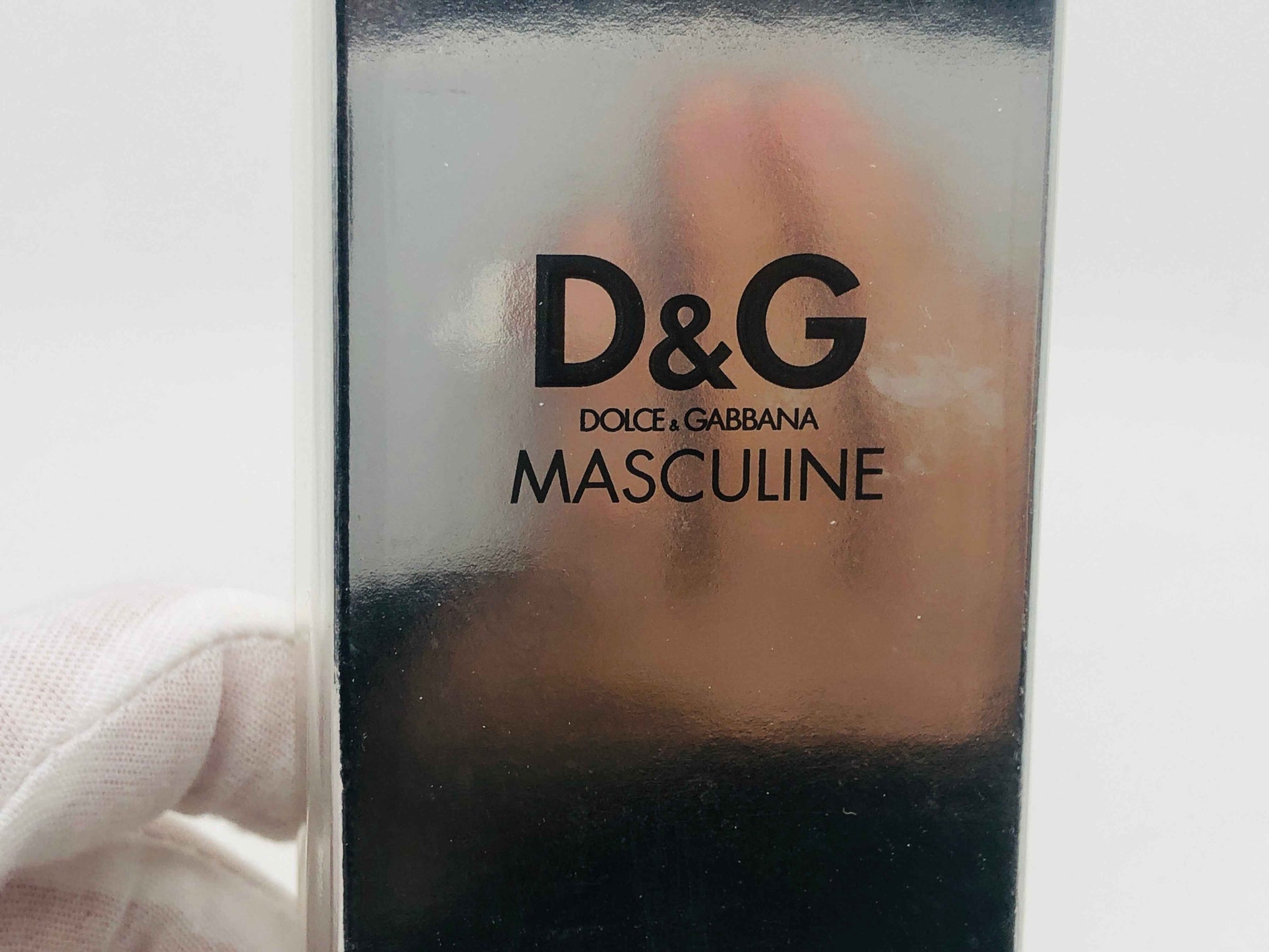 Scatola di Dolce E Gabbana Masculine con marchio D&G stampato in nero su fondo argentato