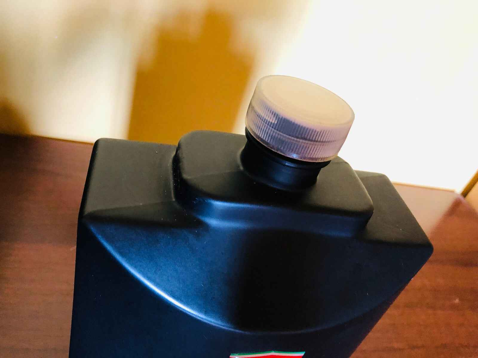 Flacone di profumo Ferrari Black Vintage con tappo trasparente su una superficie di legno