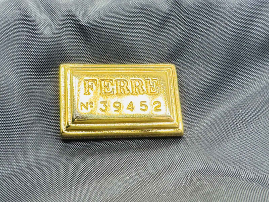 Marchio dorato FERRE N° 39452 su un tessuto nero per il profumo Ferre Gff Profumo Vintage
