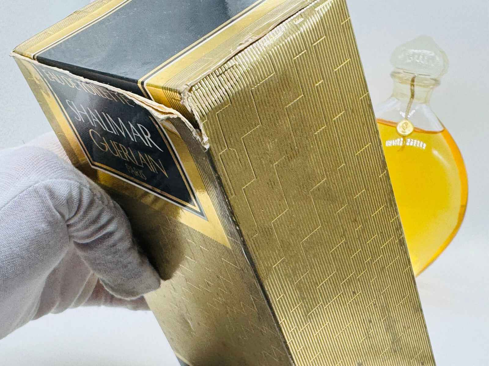 Scatola vintage di Guerlain Shalimar con profumo dorato visibile sullo sfondo per collezionisti