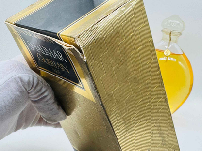 Scatola vintage di Guerlain Shalimar con profumo dorato visibile sullo sfondo per collezionisti