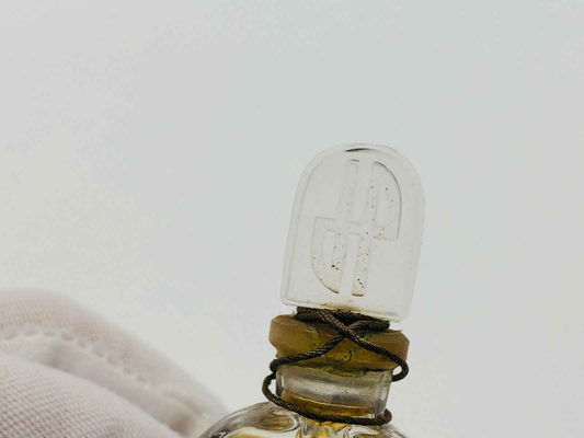 Dettaglio del tappo di una bottiglia di profumo Jean Patou Vintage con logo distintivo