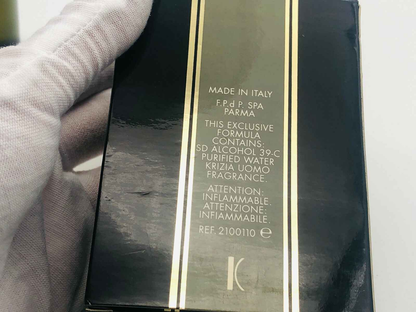 Confezione nera del Profumo Krizia Uomo Vintage con dettagli dorati tenuta da mano con guanto bianco