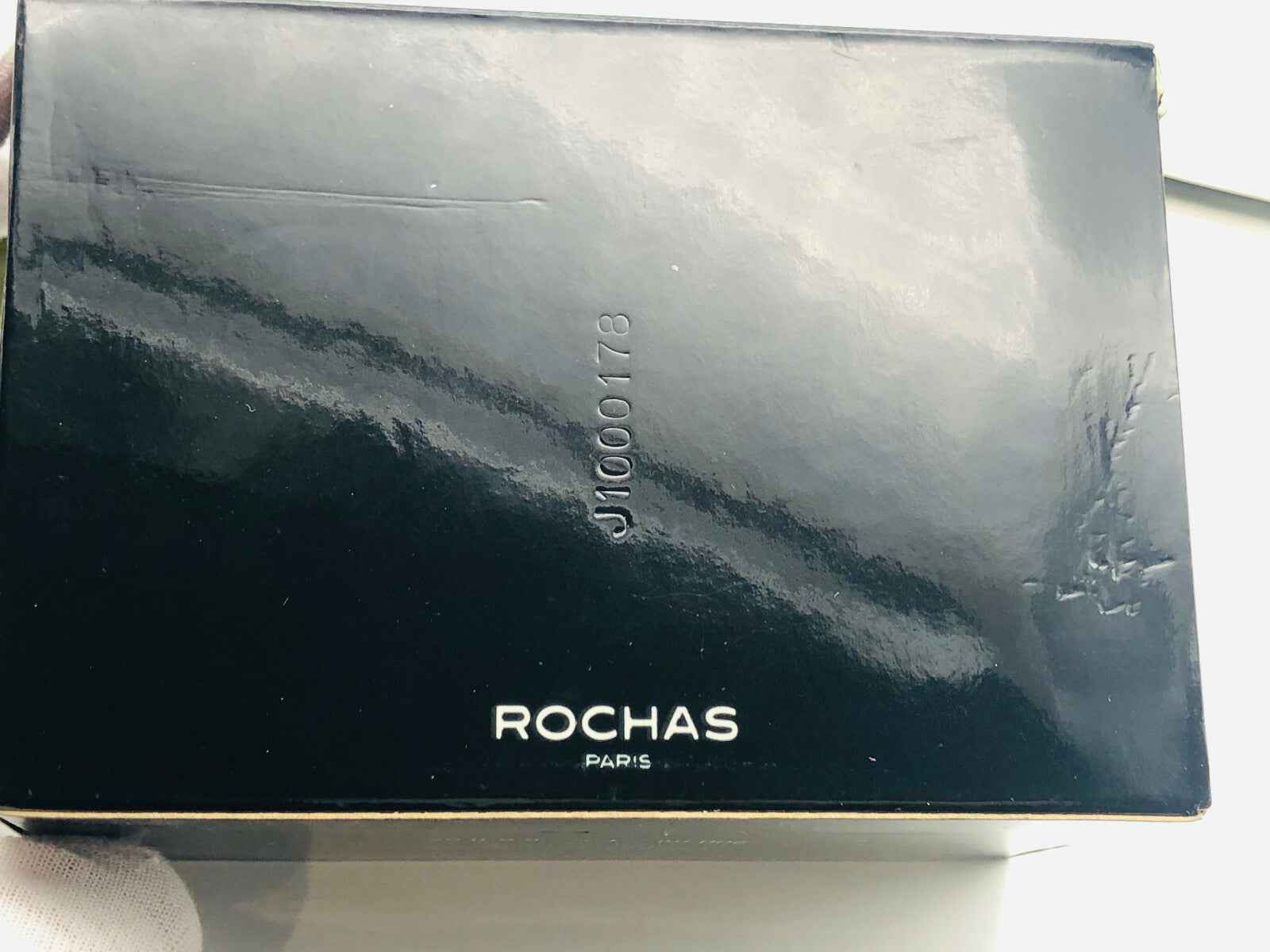 Scatola di profumo Macassar Rochas Vintage con logo Rochas in oro su fondo nero lucido