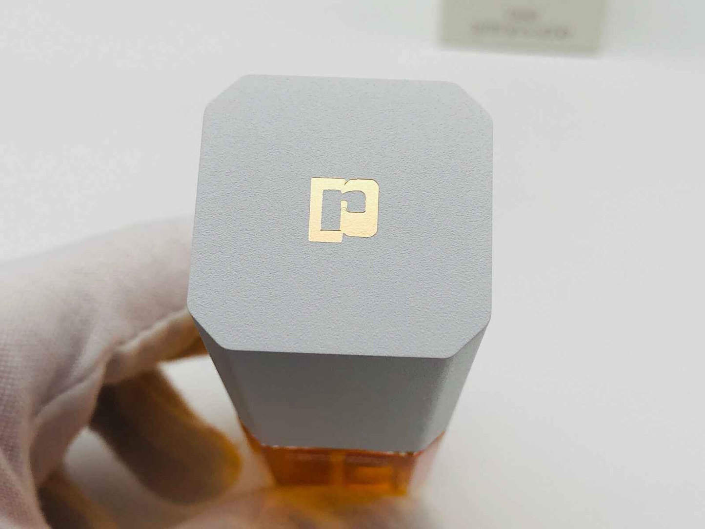 Dettaglio del tappo grigio del profumo Paco Rabanne Eau De Metal con logo dorato