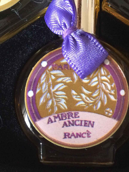 Flacone di profumo Rance Ambre Ancien con etichetta decorativa e nastro viola