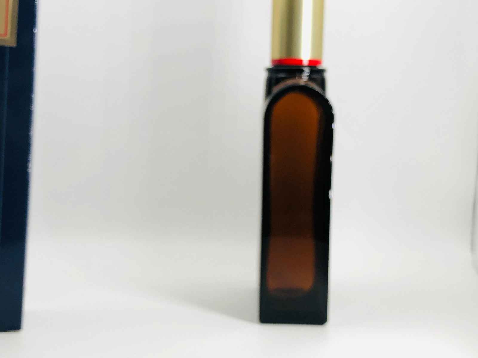 Flacone di profumo Aramis 900 in vetro scuro con tappo dorato e design elegante