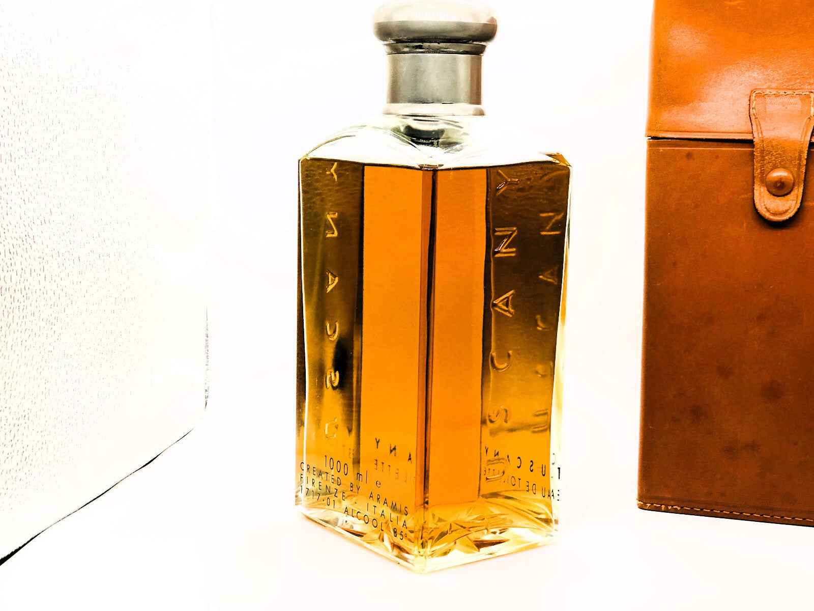 Flacone di profumo Aramis Tuscany Vintage con design elegante accanto a un astuccio in pelle