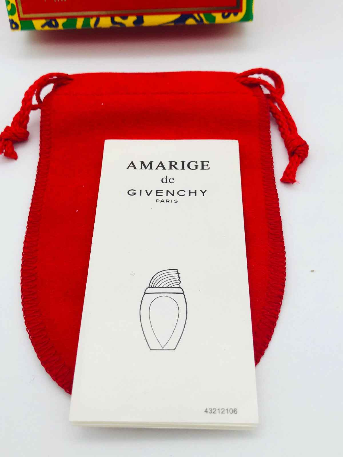 Campione di profumo Givenchy Amarige con packaging elegante su sfondo rosso
