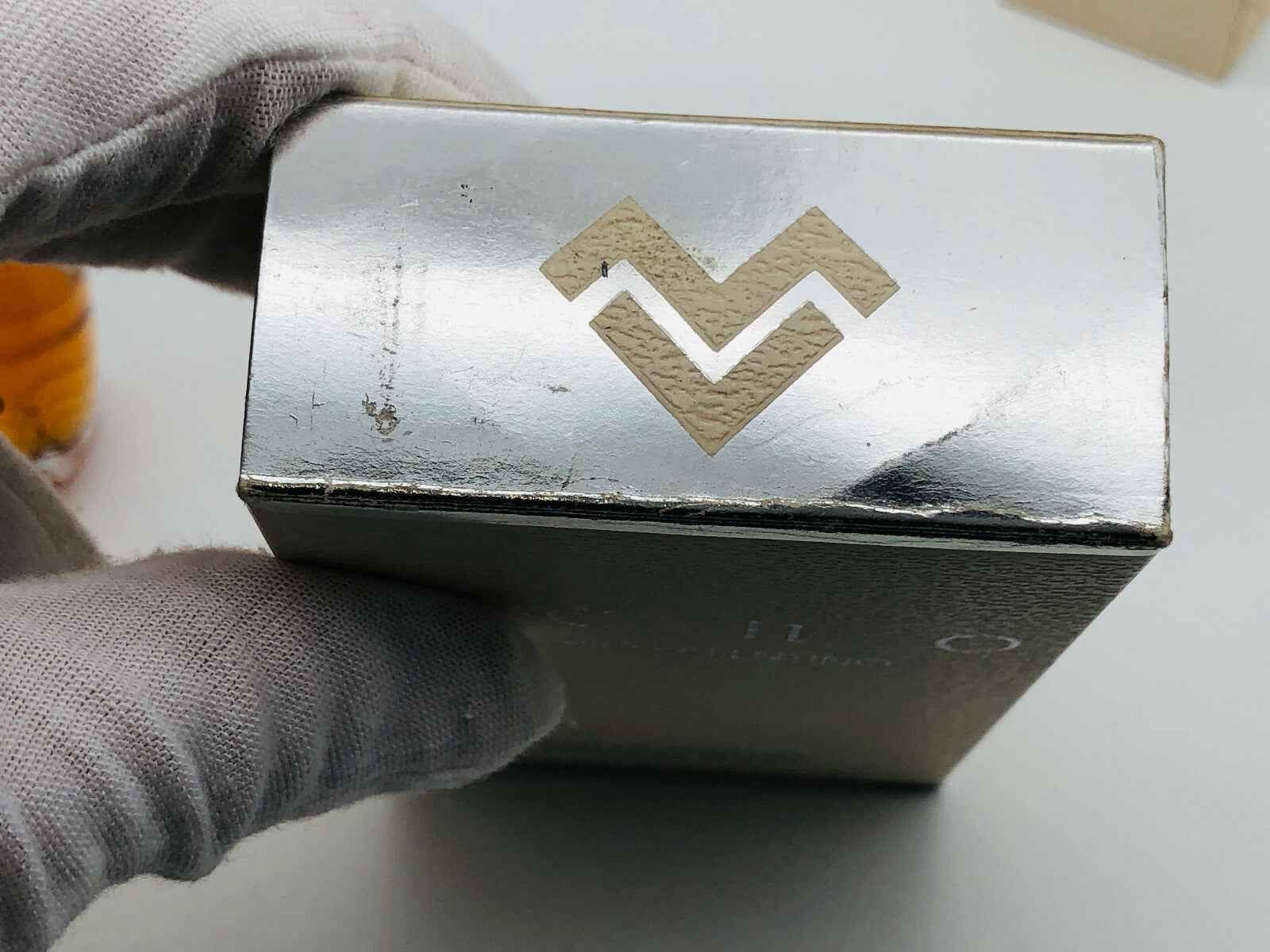 Scatola del profumo Mario Valentino Echo con logo in rilievo su fondo metallico