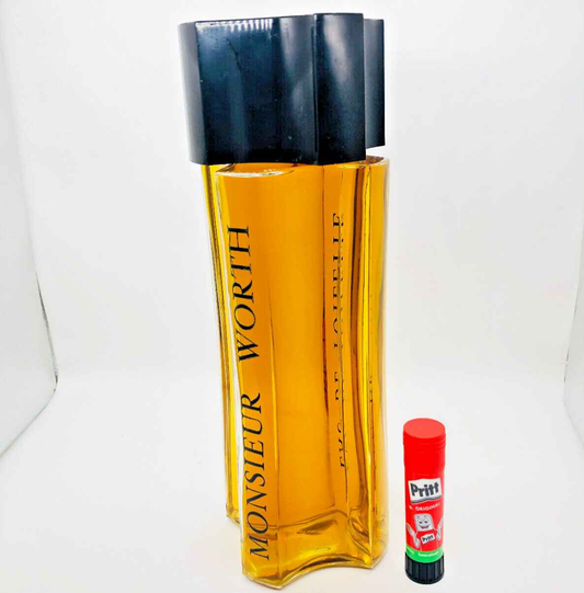 Flacone di profumo Monsieur Worth in vetro trasparente con etichetta nera e stick di colla Pritt per confronto