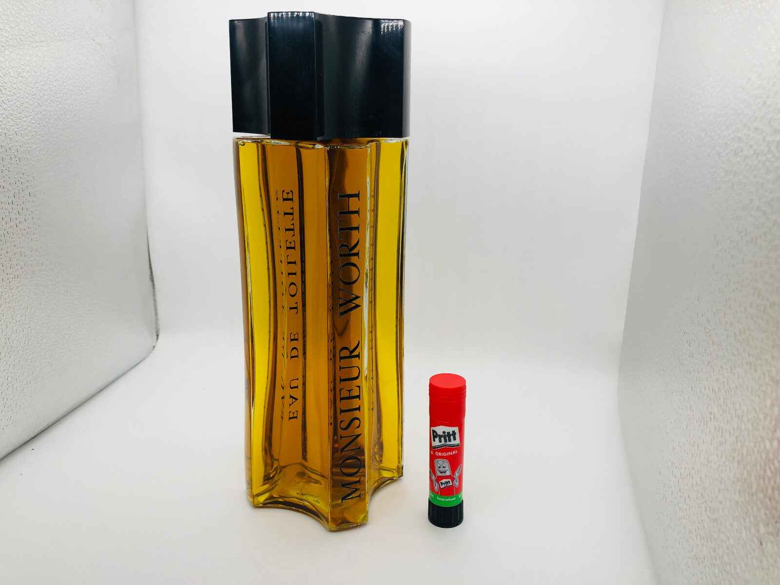Profumo Monsieur Worth in bottiglia elegante, con tonalità ambrate e design distintivo affiancato da un balsamo labbra