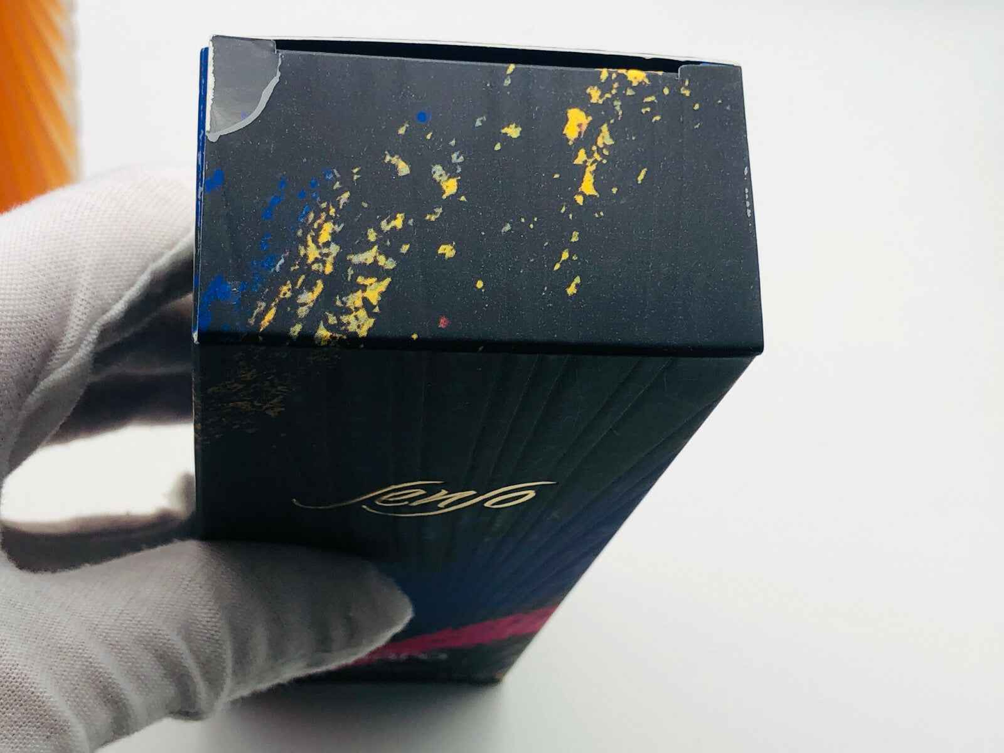 Scatola del Profumo Senso Ungaro con design artistico e colori vivaci, tenuta con una mano guantata
