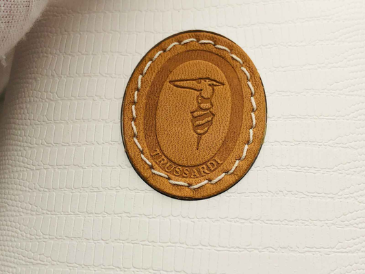 Etichetta in pelle con logo Trussardi su una borsa elegante, rappresentativa del profumo Trussardi Donna Vintage