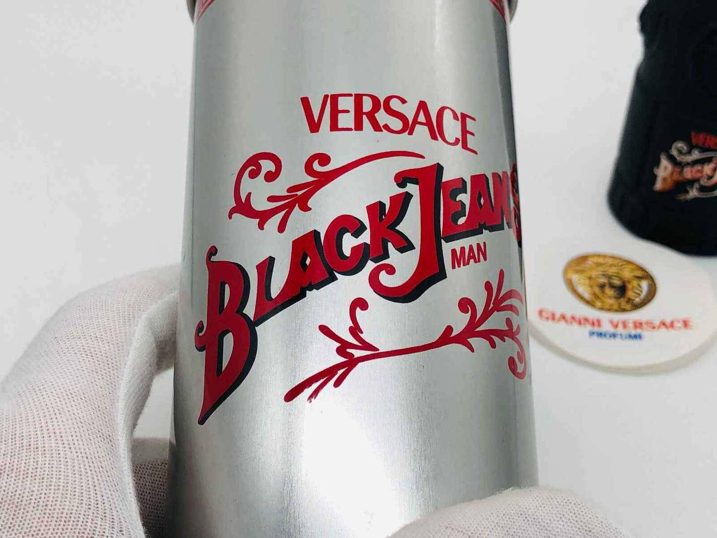 Flacone di profumo Versace Black Jeans con design elegante e testo rosso su sfondo argentato