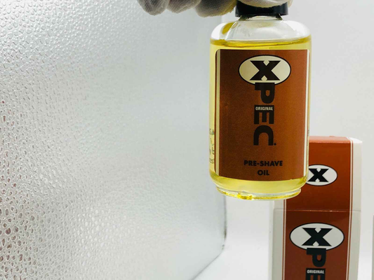 Flacone di olio pre barba Xpec con etichetta marrone e confezione elegante sullo sfondo